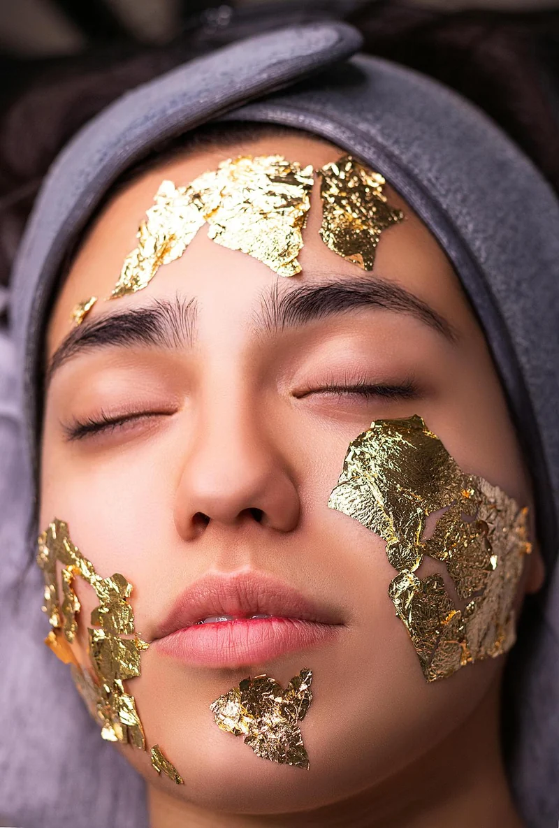 Retrato de una mujer con los ojos cerrados y láminas de oro en el rostro